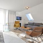 Wohn- und Essbereich mit Sofa, Sessel und TV. Dachfenster und große Fenster.