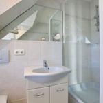 Badezimmer mit Dusche, Waschbecken und Spiegel unter Dachschräge