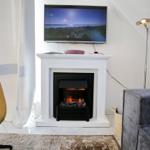 Wohnzimmer mit Kamin, Fernseher und Sitzgelegenheiten.