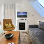 Wohnzimmer mit Sofa, Sessel, Fernseher und Kamin