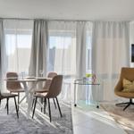 Essbereich mit Tisch und Stühlen, Sitzgelegenheit und Fernseher an der Wand.