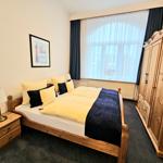 Schlafzimmer mit Holzbett, Kleiderschrank und Fenster mit Vorhängen.
