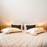 Schlafzimmer mit Bett, Kissen und Holz Kopfteil unter schrägen Decken.