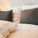 Bettkopf mit Fellkissen und grauen Kissen
