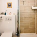 Bad mit Dusche, Toilette und kleinen Dekorationsgegenständen an der Wand.