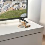 TV auf weißem Möbelstück mit Strandbild und Sandalen darauf.