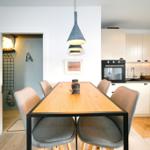 Essbereich mit Tisch und Stühlen, Küche mit weißen Schränken und Dunstabzug.