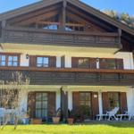 A two-story house with balconies and a garden. White chairs are outside.