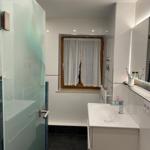 Bathroom with shower, sink, and window.