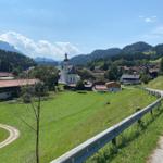 Wide view of a scenic mountain landscape with church and villages.