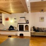Living room with fireplace, sofa, and seating area. Wooden ceiling and hardwood floor.