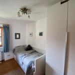 A bedroom with bed, wardrobe, and window with curtain.