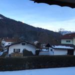 Snow-covered view of houses and mountains at dusk.