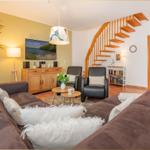 Wohnzimmer mit Sofa, Fernseher und Holztreppe.