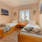 Zwei Schlafzimmer mit Holzbetten und Fenster.