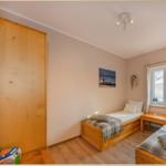 Zwei Schlafzimmer mit Holzbetten, Fenster und Wandbildern.
