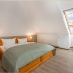 Schlafzimmer mit Dachschräge, Bett, Nachttisch und Fenster.