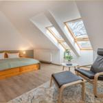 Schlafzimmer mit Dachschrägen, Dachfenstern, Bett und Sessel.