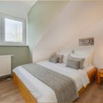 Schlafzimmer mit Dachschrägen, Bett, Nachttisch und Fenster.