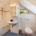 Badezimmer mit Badewanne, Waschbecken und Toilette unter Dachschräge mit Dachfenster.