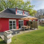 Rotes Haus mit Terrasse, Garten und Sitzgruppe unter Sonnenschirm.