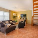 Wohnzimmer mit Sofa, Sessel und Holztreppe.