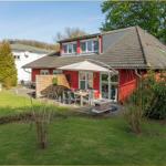 Rotes Haus mit Garten, Terrasse und Sonnenschirm. Holzumzäunung und Grillplatz.