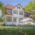 Ein großes Haus mit Terrasse und Gartenbereich mit Sonnenschirmen.