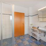 Badezimmer mit Dusche, Waschbecken und Spiegel