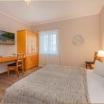 Schlafzimmer mit Bett, Schreibtisch, Kleiderschrank und Fenster.