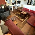 Wohnzimmer mit rotem Sofa, Kamin und Teppich auf Fliesenboden.