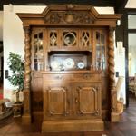 Großes Holzschrankmöbel mit Glasfronten und dekorativen Elementen im Eingangsbereich.