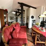 Erdgeschoss mit rotem Sofa, Holztisch und Kaminofen.