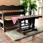 Holzbank und Tisch mit Tischdecke auf Teppich im Raum mit Terrakottaboden.