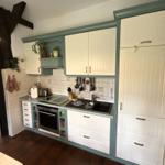 Küche mit weißen Schränken, grünem Rahmen und Backofen.