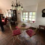 Essbereich mit runden Tisch und Stühlen, Fenster und Wanduhr.