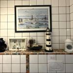 Bad mit Fliesenwand, Seemotivbild und Seehandwerk dekoriert.