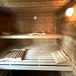 Sauna mit Holzbanken und Temperaturmessgerät an der Wand.