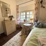 Schlafzimmer mit Bett, Schrank, Spiegel und Fenster mit Vorhängen.