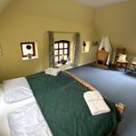 Schlafzimmer mit Bett, Fenstern und Holzmöbeln.