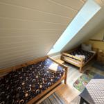 Zimmer mit zwei Betten, Dachschräge und Dachfenster. Holzbett, Teppich und Tisch.