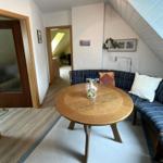 Wohnzimmer mit Schlafcouch, runden Tisch und schrägen Dachbodenwänden.