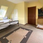 Schlafzimmer mit Dachschrägen, Bett, Kinderbett und Fenster