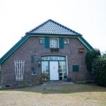 Ein Backsteinhaus mit grünen Fensterläden und einer weißen Haustür.