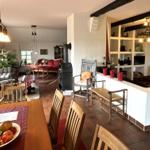 Wohn- und Essbereich mit Holztisch, Stühlen und Kaminofen. Terrakottaboden und Holzbalken.