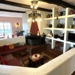 Wohnbereich mit Kamin, Sitzbank und weißen Regalen. Holzdeckenbalken und Fliesenboden.