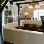 Wohn- und Essbereich mit Kamin, Holzbalken und rustikaler Einrichtung.