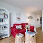 Ein Wohnzimmer mit rotem Sofa, weißen Regalen und Holzboden.