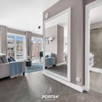 Wohnbereich mit Sofa, Spiegel und Dusche im Hintergrund.