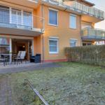 Orangerotes Haus mit Balkon, Terrasse und Garten. Durchgangstür zum Innenraum.